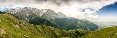 Панорама заснеженного хребта и зеленых склонов над равниной, Дхарамсала
