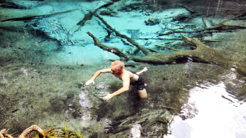 Мужчина плавает в прозрачной бирюзовой воде Emerald Pool, Краби