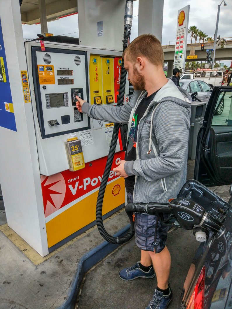 Мужчина заправляет машину на заправке Shell, США