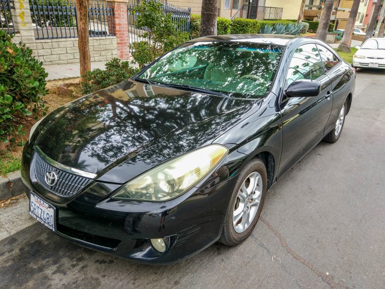 Черная Toyota Solara у тротуара, вид спереди сбоку