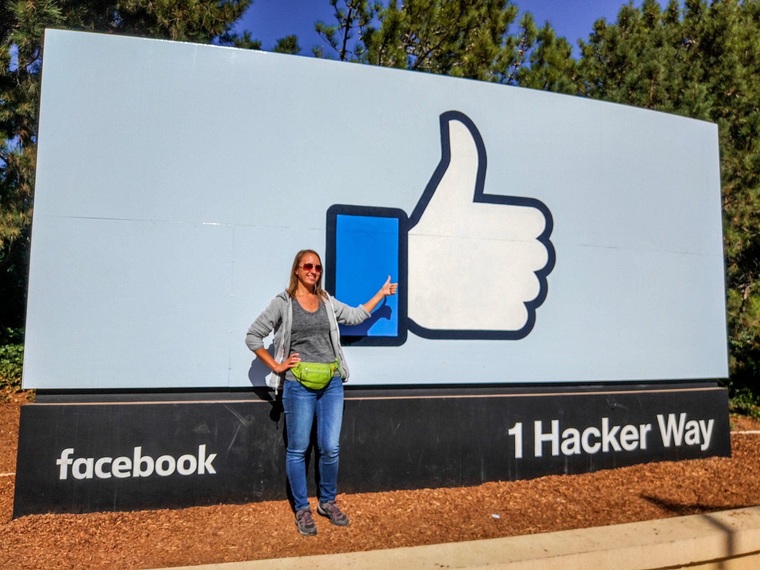 Женщина показывает на огромный знак «лайк» у въезда в штаб-квартиру Facebook, 1 Hacker Way