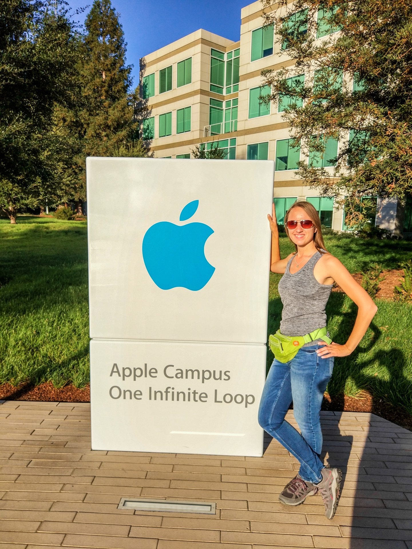 Женщина у знака Apple Campus, One Infinite Loop, на фоне офисного здания