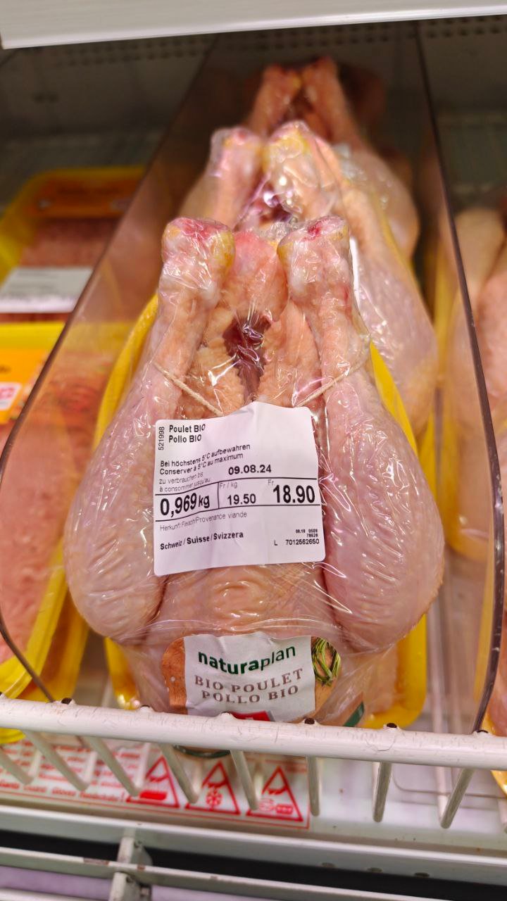 Курица в упаковке с ценником на полке магазина