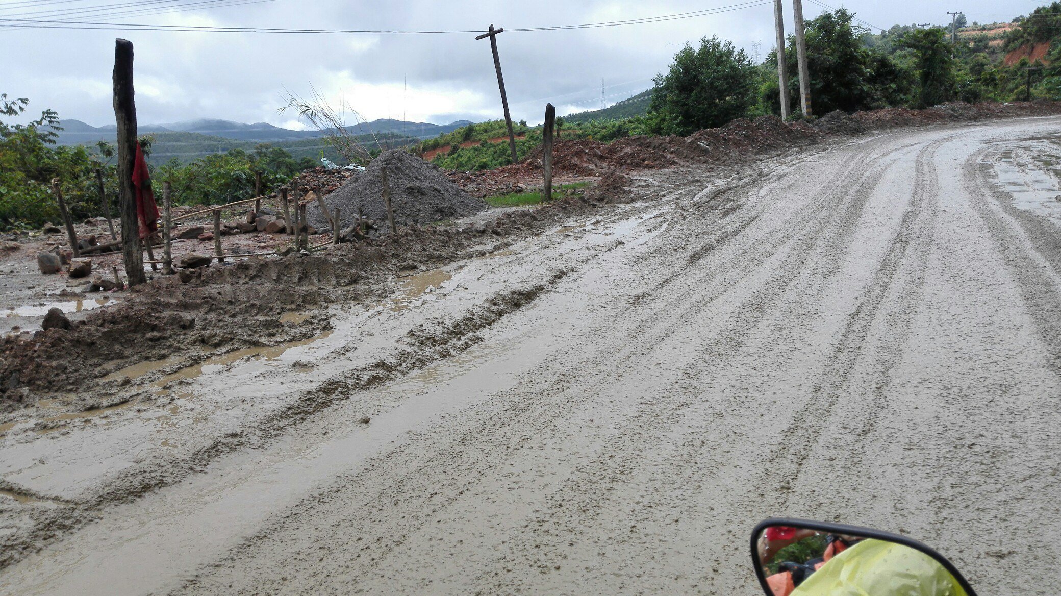Раскисшая грязная дорога после дождя, в углу кадра зеркало скутера